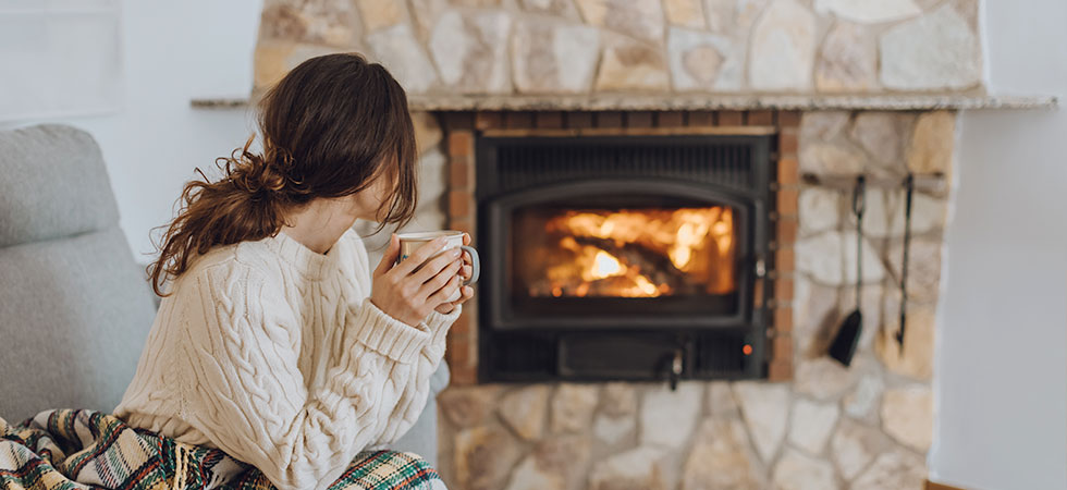 Woman staring at cozy wood fireplace